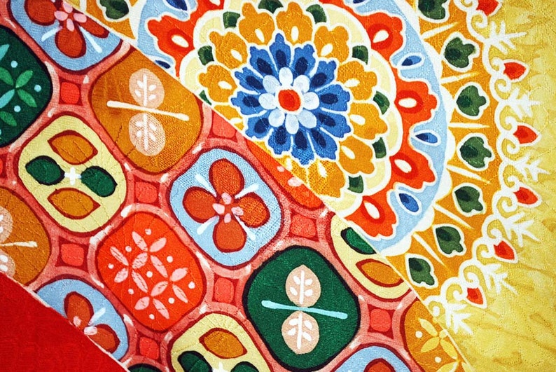 May include: A colourful fabric with a repeating pattern of geometric shapes and flowers. The fabric is a mix of red, orange, yellow, green, blue and white.