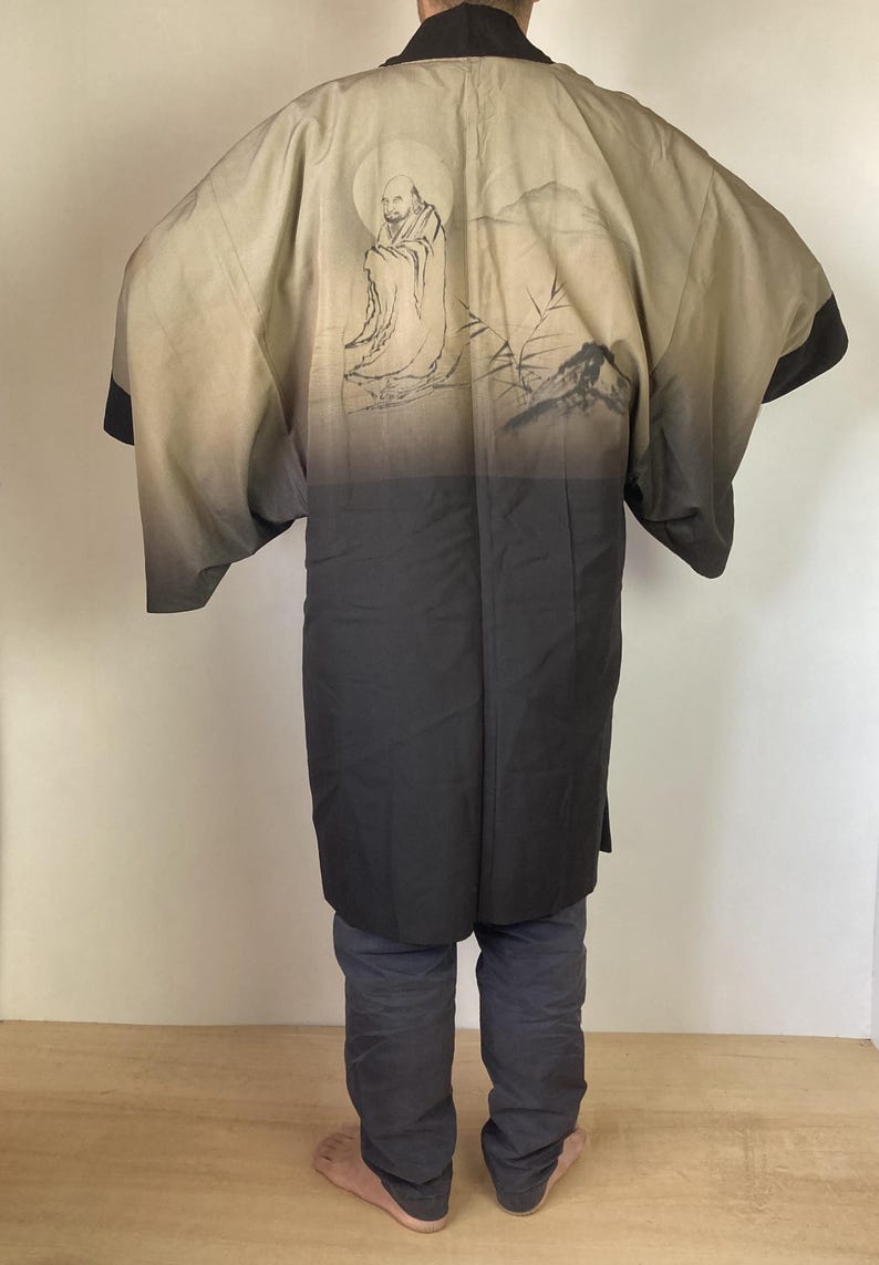 May include: A black and beige Japanese kimono with a traditional design of a figure sitting under a full moon. The kimono has a gradient design, fading from beige to black.