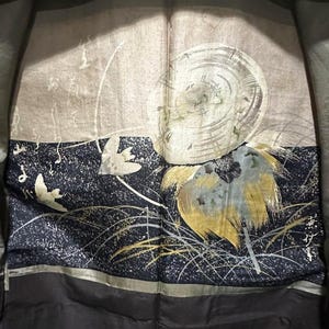 May include: A black silk kimono with a gold and silver design of a bird and a flower. The design is on a dark blue background with white speckles.