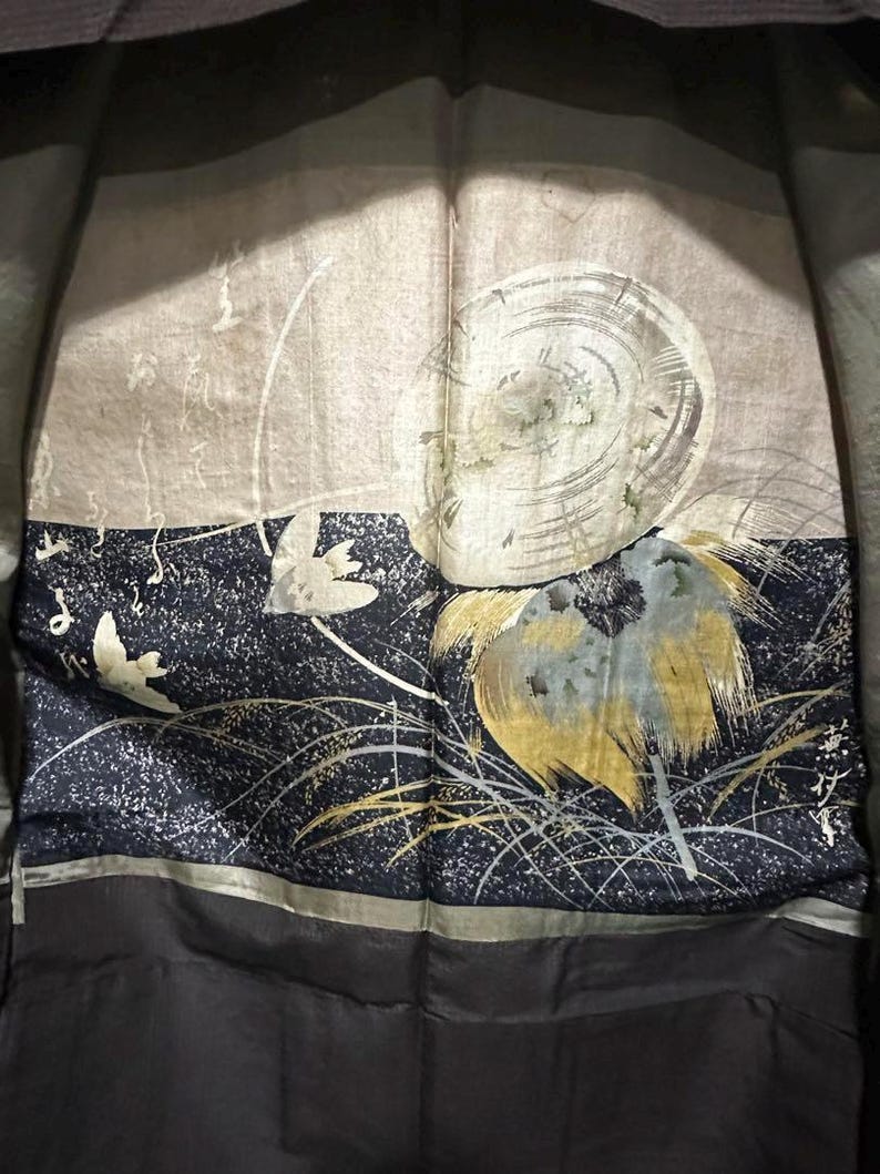May include: A black silk kimono with a gold and silver design of a bird and a flower. The design is on a dark blue background with white speckles.