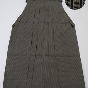 Puede incluir: Un hakama a rayas negras y doradas, una prenda tradicional japonesa que usan los hombres, con un primer plano del patrón de la tela.