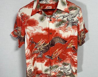May include: Short-sleeved button-up shirt with a vibrant dragon design. The shirt features a red and white color scheme with a detailed illustration of a dragon, clouds, and trees. The shirt is hanging on a wooden hanger.
