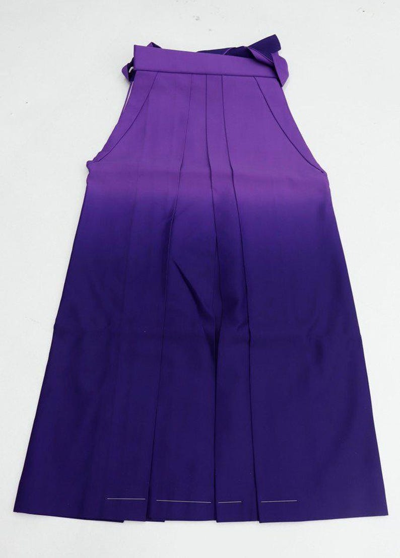 May include: A purple and dark purple ombre hakama with pleats and a tie at the waist.