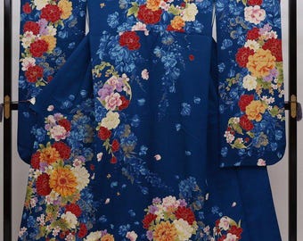 May include: A vibrant blue kimono with a floral pattern. The design features large, colorful flowers in shades of red, yellow, and white, set against a deep blue background. The sleeves and body are fully decorated.