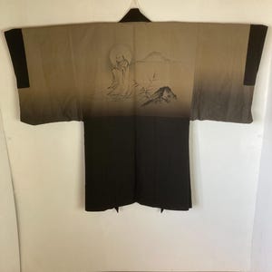 May include: A traditional Japanese robe, or "yukata", with a black and brown color scheme. The robe features a hand-painted design of a figure sitting in a landscape with a mountain and a moon.