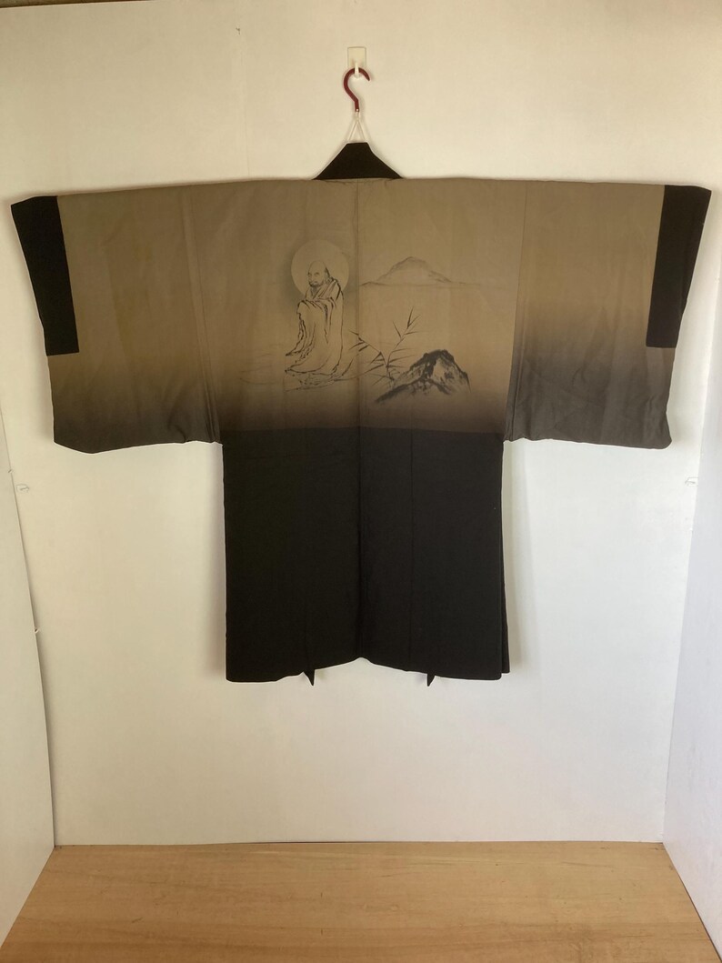 May include: A traditional Japanese robe, or "yukata", with a black and brown color scheme. The robe features a hand-painted design of a figure sitting in a landscape with a mountain and a moon.