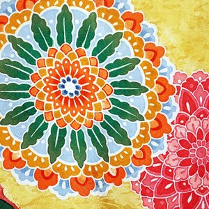 May include: A yellow fabric with a large orange, red and blue floral design. The design is surrounded by green leaves. A smaller pink floral design is in the bottom right corner.