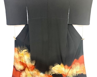 May include: A black kimono featuring wide sleeves and three small circular crests along the upper back. The lower portion displays a gradient transition into a deep red hue, decorated with gold-toned crane motifs and stylised floral patterns.