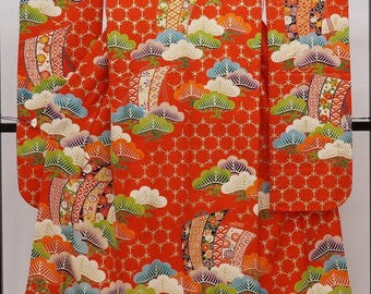 May include: A red kimono with a traditional Japanese pattern of stylized clouds and pine trees. The kimono is decorated with gold and silver thread embroidery.