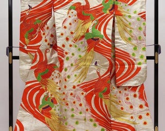May include: A traditional Japanese kimono with a cream-colored background and a vibrant design featuring red and orange swirling patterns. The kimono is adorned with embroidered peacocks in shades of red, green, and yellow, creating a striking visual.