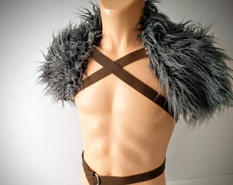 May include: A brown faux leather harness featuring crisscross chest straps and a waist belt with a silver-toned metal ring, accented by voluminous gray faux fur shoulder pieces that drape over the upper chest and back area.