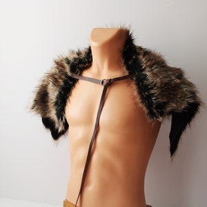 May include: A brown faux fur shoulder wrap with a brown leather strap. The strap has a metal ring and is adjustable.