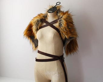 May include: A brown faux fur shoulder wrap with a brown leather strap across the chest.