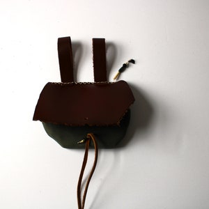 May include: A small brown leather pouch and a drawstring closure. The pouch has two leather straps for carrying.