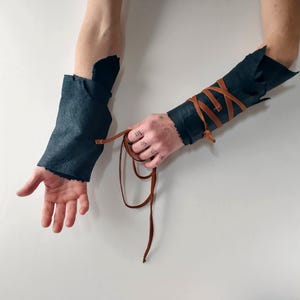 dark sheepskin arm wraps with leather straps untying