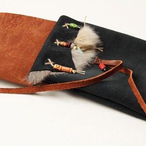 the dark blue suede pouch is lying open and the fur trim and ornamental beads are visible