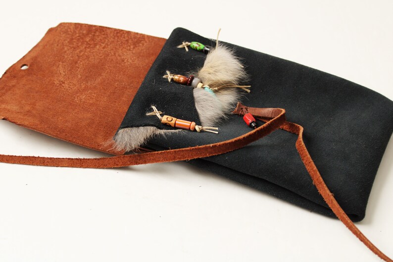 the dark blue suede pouch is lying open and the fur trim and ornamental beads are visible