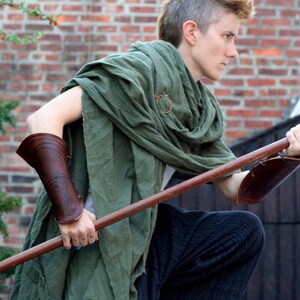 the drab green shawl is draped loosely around the shoulders and body