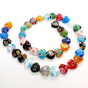May include: A strand of colorful glass heart beads with floral patterns. The beads are strung on a clear thread and are arranged in a circle.