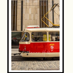 May include: A framed photograph of a red and cream tram in a city. The tram has the number 8544 on its side. The photograph is signed "Katharine Hill PHOTOGRAPHY".