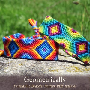 Może przedstawiać: Dwa kolorowe bransoletki przyjaźni z geometrycznym wzorem diamentów. Bransoletki są wykonane z tęczowej nici do haftowania i leżą na szarym kamieniu.