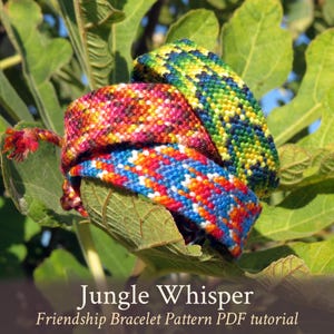 Op de afbeelding: Drie kleurrijke vriendschapsarmbanden, een groen, geel en blauw, een rood, oranje, geel en blauw, en een rood, oranje, wit en blauw, liggen op elkaar gestapeld op een groen blad. De armbanden zijn gemaakt van borduurgaren en hebben een geweven patroon. De tekst "Jungle Whisper Friendship Bracelet Pattern PDF tutorial" staat onderaan de afbeelding.