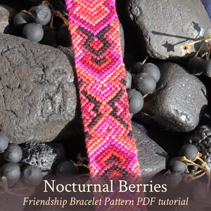May include: A colorful friendship bracelet with a geometric pattern in shades of pink, red, and black. The bracelet is made with embroidery floss and is lying on a bed of black stones. The text "Nocturnal Berries" and "Friendship Bracelet Pattern PDF tutorial" is displayed below the bracelet.