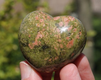May include: A heart-shaped green and pink stone with a speckled pattern.