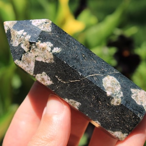 Könnte beinhalten: Ein dunkelgrüner und cremefarbener Edelstein-Obelisk. Der polierte Stein hat eine rechteckige Form mit einer spitzen Spitze. Die Oberfläche ist mit cremefarbenen Flecken und Adern gesprenkelt.