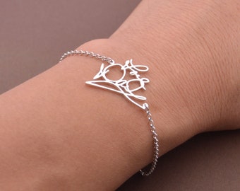 May include: A silver chain bracelet with a delicate, handwritten-style pendant. The pendant is a stylized signature.