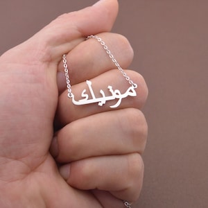 May include: Silver necklace with the Arabic word "Joubran" written in a delicate script.