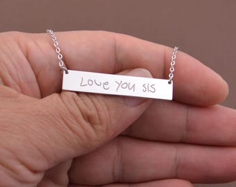 May include: Silver necklace with a bar pendant that says "Love you sis" in handwritten font.