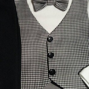 May include: A black and white houndstooth vest with three black buttons. The vest is paired with a white bodysuit and a black and white houndstooth bow tie. The bodysuit has a label that reads "carter's" and "24".