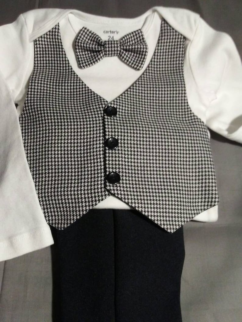 May include: A black and white houndstooth vest with black buttons, a black bow tie, a white bodysuit with the text "carter's 24", and black pants.