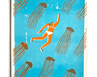 May include: A blue and orange print of a person swimming in a sea of jellyfish. The print is titled "Max Machen".