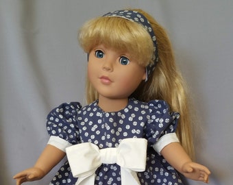 18 inch doll Christmas dress in navy fabric with white jingle bells and large white waistline bow