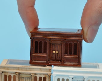 Könnte beinhalten: Drei Miniatur-Ladenfronten, eine braune, eine beige und eine weiße, mit Glasfenstern und Türen. Die braune Ladenfront wird von einer Hand gehalten.