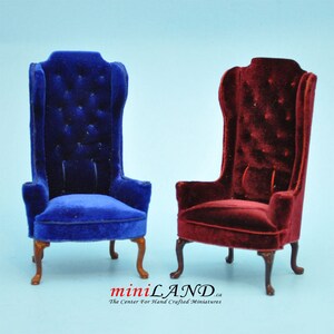 May include: Two miniature velvet wingback chairs, one in blue and one in burgundy red. The chairs have a tufted back and are on wooden legs.