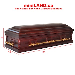 May include: A miniature wooden coffin with gold accents. The coffin is 2.75 inches wide, 1.25 inches long, and 2 inches tall. miniLAND.ca The Center For Hand Crafted Miniatures