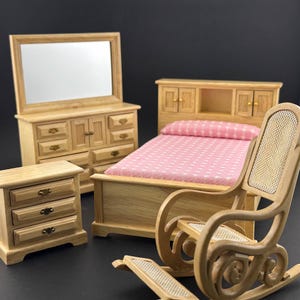 May include: A wooden dollhouse bedroom set with a bed, dresser, nightstand, and rocking chair. The bed has a pink and white patterned bedding. The dresser has a mirror on top.