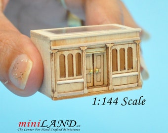Könnte beinhalten: Ein Miniaturgebäude aus Holz mit einem Glasdach, zwei Fenstern und einer Doppeltür. Das Gebäude ist im Maßstab 1:144.