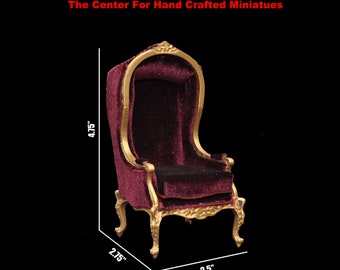 May include: A miniature burgundy velvet armchair with gold trim and a high back. The chair measures 4.75 inches tall, 2.75 inches wide, and 2.5 inches deep.