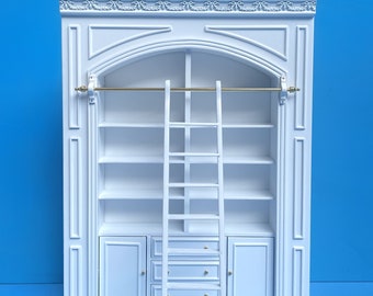 May include: White wooden bookshelf with a ladder, featuring a decorative arched top and a gold rod. The bookshelf has five shelves, two drawers, and two doors. The ladder is labeled "Y9110L WH".