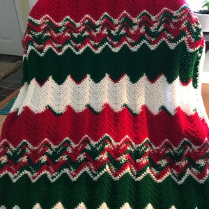 Puede incluir: Una manta de ganchillo con un patrón de chevron en rojo, blanco y verde.
