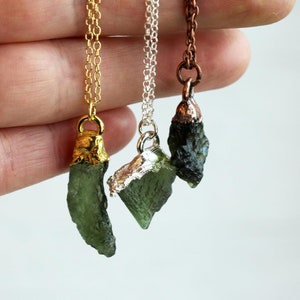 May include: Three necklaces with green tektite stone pendants. The pendants are wrapped in gold, silver, and copper wire.
