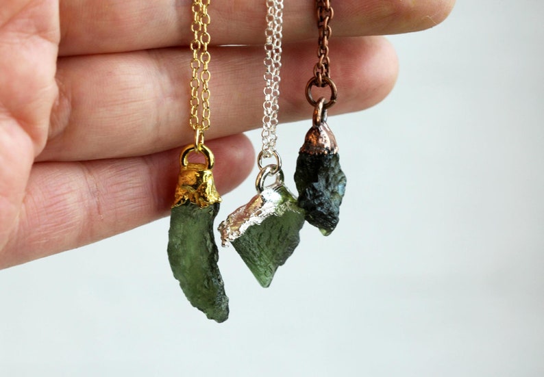 May include: Three necklaces with green tektite stone pendants. The pendants are wrapped in gold, silver, and copper wire.