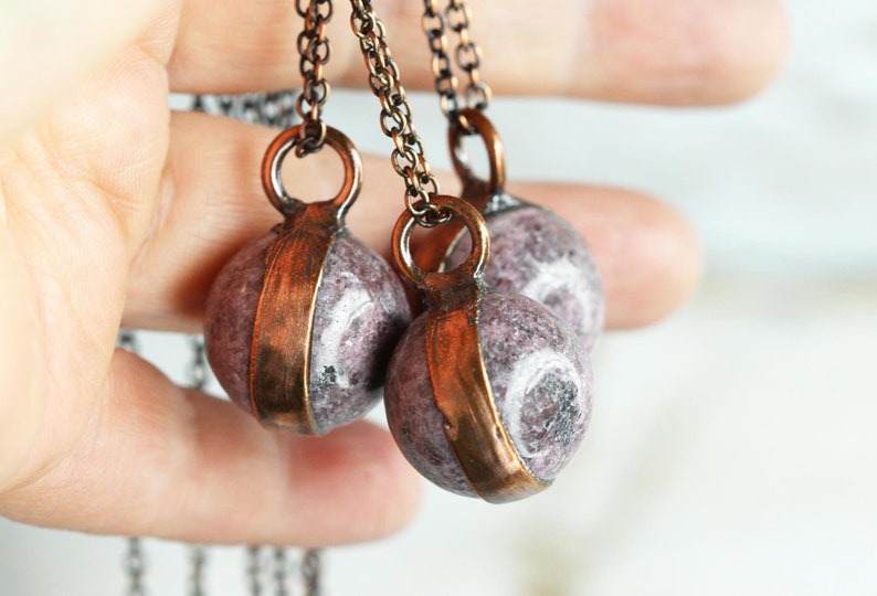 May include: Three necklaces with copper chain and round, purple and white stone pendants.