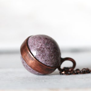 May include: A copper and purple stone pendant necklace. The pendant is a sphere with a copper band around the middle. The necklace is made of a copper chain.
