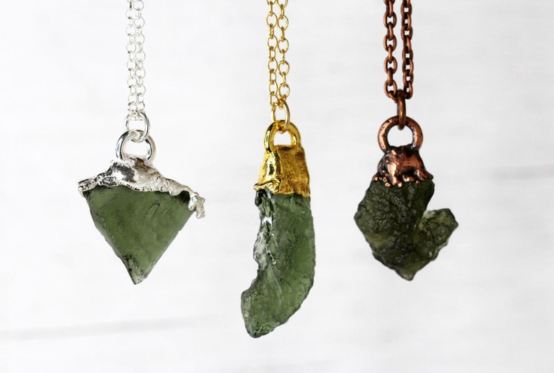 May include: Three necklaces with green gemstone pendants. The pendants are set in silver, gold, and copper.
