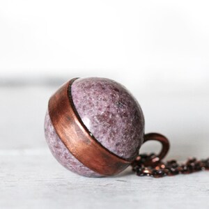 May include: A copper and purple stone pendant necklace. The pendant is a sphere with a copper band around the middle. The necklace is made of a copper chain.